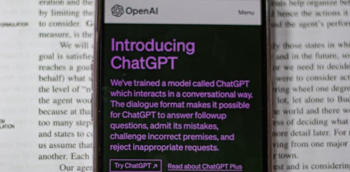 Foto di telefono con ChatGPT con in secondo piano un libro aperto che parla di AI generative