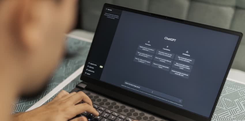 Foto di uomo davanti al computer con schermata aperta sul sito di OpenAI alla versione web desktop di ChatGPT